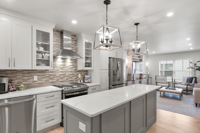 1 Howard Ave Unit C2, Norwalk, CT 06855 - kitchen with stainless steel appliances, wall chimney range hood, a center island, backsplash, and light wood finished floors