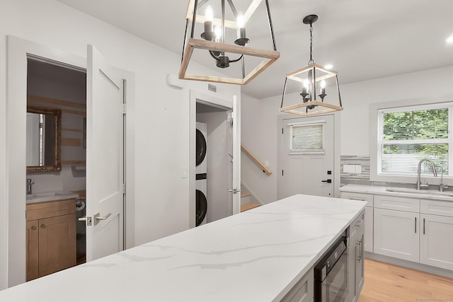1 Howard Ave Unit C2, Norwalk, CT 06855 - kitchen featuring a sink, estacked washer and dryer, a chandelier, light wood-style flooring, and white cabinets