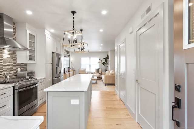 1 Howard Ave Unit C2, Norwalk, CT 06855 - kitchen with wall chimney range hood, appliances with stainless steel finishes, a chandelier, a center island, and recessed lighting
