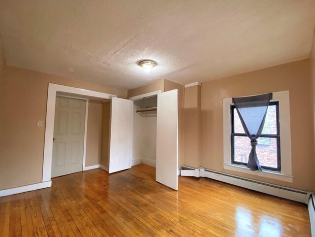 24 Townley St, Hartford, CT 06105 - unfurnished bedroom featuring hardwood / wood-style floors, a baseboard heating unit, a textured ceiling, a closet, and baseboards