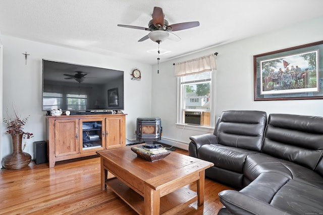 355 Farmington Ave, Bristol, CT 06010 - living room featuring a wood stove, a baseboard radiator, a ceiling fan, and light wood finished floors