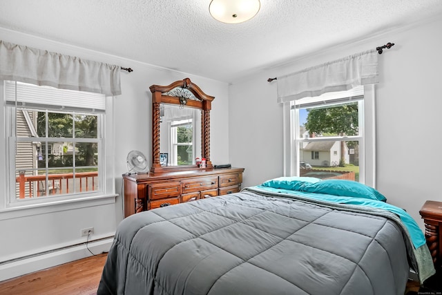 355 Farmington Ave, Bristol, CT 06010 - bedroom with baseboard heating, a textured ceiling, wood finished floors, multiple windows, and ornamental molding
