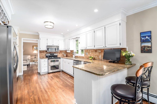 10 Hundred Acres Rd, Newtown, CT 06470 - kitchen featuring appliances with stainless steel finishes, a peninsula, a baseboard heating unit, light wood-style floors, and light stone counters