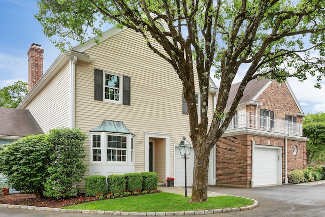 177 S Ave Unit 6, New Canaan, CT 06840 - view of front of house with a chimney, a balcony, a garage, asphalt driveway, and brick siding