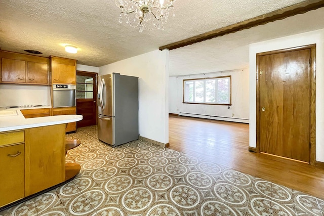 92 Milardo Ln, Middletown, CT 06457 - kitchen with stainless steel appliances, a baseboard radiator, a textured ceiling, light countertops, and brown cabinetry