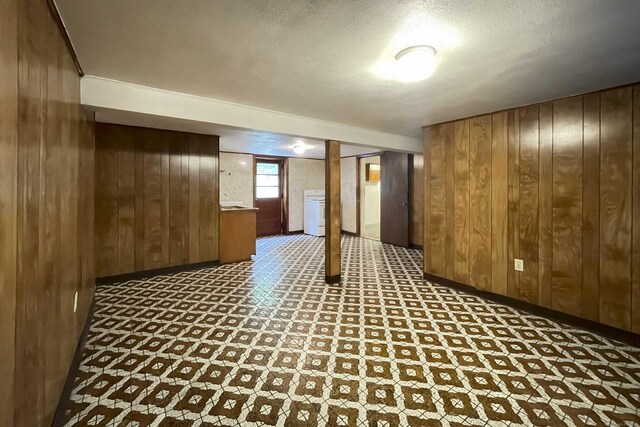92 Milardo Ln, Middletown, CT 06457 - basement with wooden walls, tile patterned floors, baseboards, a textured ceiling, and washer / clothes dryer