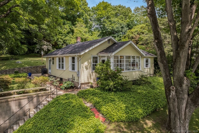 145 Main St, Essex, CT 06442 - view of front of house with a sunroom, roof with shingles, and a chimney