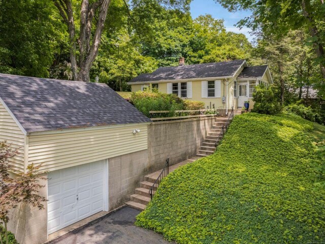 145 Main St, Essex, CT 06442 - ranch-style house featuring stairway, a garage, a chimney, asphalt driveway, and roof with shingles