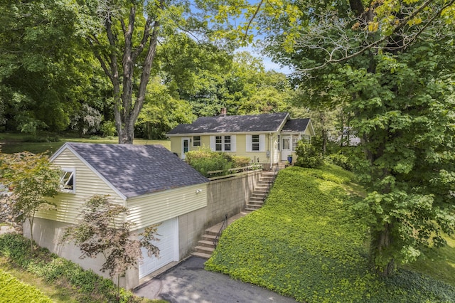 145 Main St, Essex, CT 06442 - view of front of house with stairs, a garage, a shingled roof, asphalt driveway, and view of scattered trees