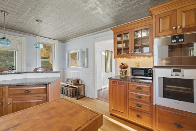 70 River Rd, East Haddam, CT 06423 - kitchen with stainless steel appliances, an ornate ceiling, brown cabinetry, glass insert cabinets, and wainscoting