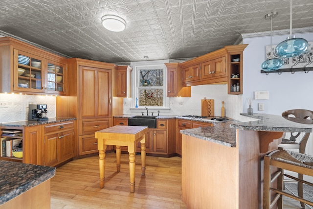 70 River Rd, East Haddam, CT 06423 - kitchen featuring a sink, an ornate ceiling, a peninsula, decorative backsplash, and brown cabinets