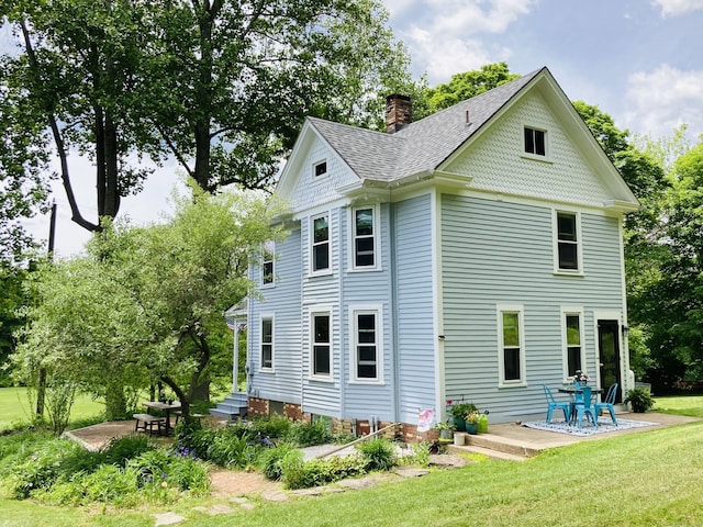 70 River Rd, East Haddam, CT 06423 - back of house featuring a patio area, a chimney, a lawn, and roof with shingles