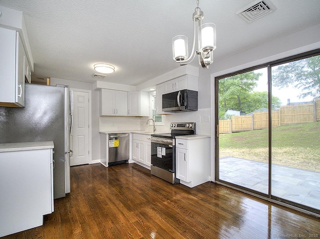 179 Anns Farm Rd, Hamden, CT 06518 - kitchen with stainless steel appliances, light countertops, dark wood-type flooring, white cabinetry, and a chandelier