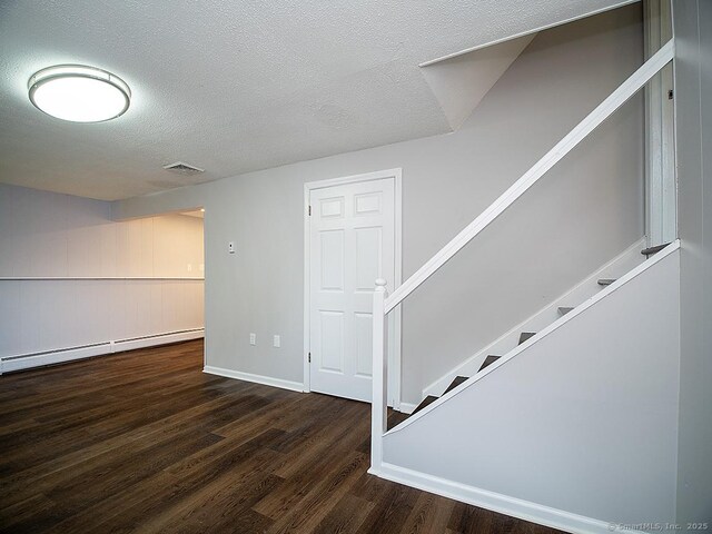 179 Anns Farm Rd, Hamden, CT 06518 - below grade area featuring a baseboard heating unit, wood finished floors, stairs, a textured ceiling, and baseboards