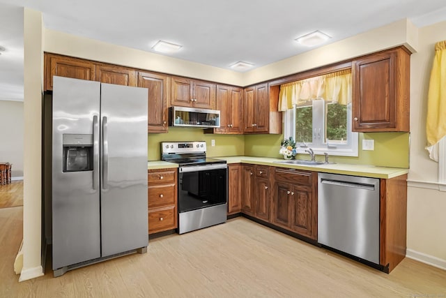 27 Kitcher Ct, Trumbull, CT 06611 - kitchen with appliances with stainless steel finishes, light wood-style floors, light countertops, a sink, and brown cabinetry