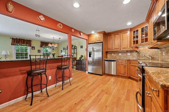 156 Governor Trumbull Way Unit 156, Trumbull, CT 06611 - kitchen featuring appliances with stainless steel finishes, a breakfast bar area, light wood-style floors, decorative backsplash, and recessed lighting
