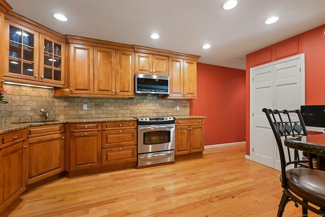 156 Governor Trumbull Way Unit 156, Trumbull, CT 06611 - kitchen featuring appliances with stainless steel finishes, light wood-type flooring, tasteful backsplash, light stone countertops, and brown cabinets