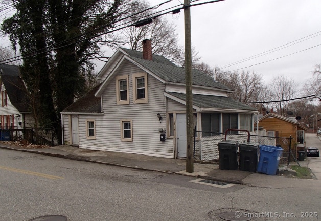 231 Broad St, Norwich, CT 06360 - view of front of home with a chimney, a sunroom, and roof with shingles