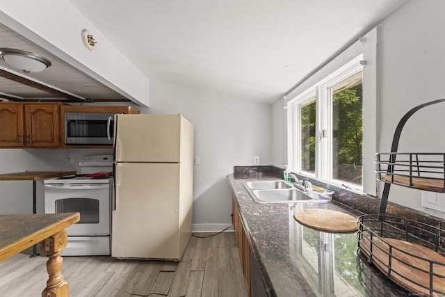 231 Broad St, Norwich, CT 06360 - kitchen featuring white appliances, light wood-style flooring, a sink, brown cabinetry, and baseboards