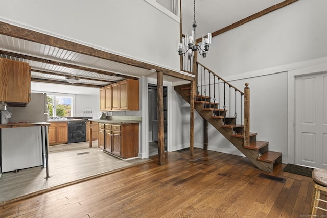 231 Broad St, Norwich, CT 06360 - kitchen with freestanding refrigerator, light wood-style floors, black dishwasher, brown cabinets, and a towering ceiling