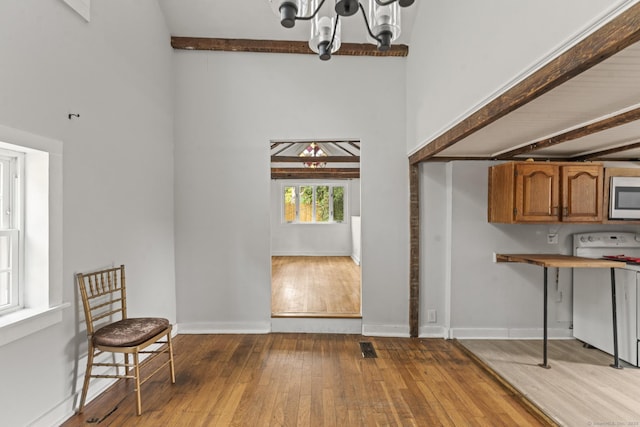 231 Broad St, Norwich, CT 06360 - kitchen with white electric stove, brown cabinetry, stainless steel microwave, wood-type flooring, and a towering ceiling