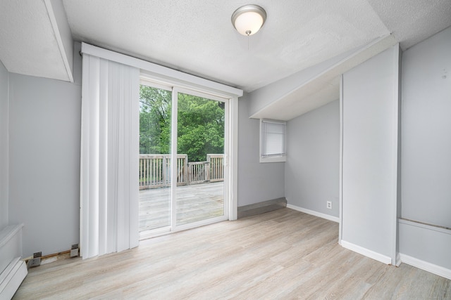 74 Mill St, Middletown, CT 06457 - empty room with a baseboard heating unit, light wood-style flooring, a textured ceiling, and baseboards