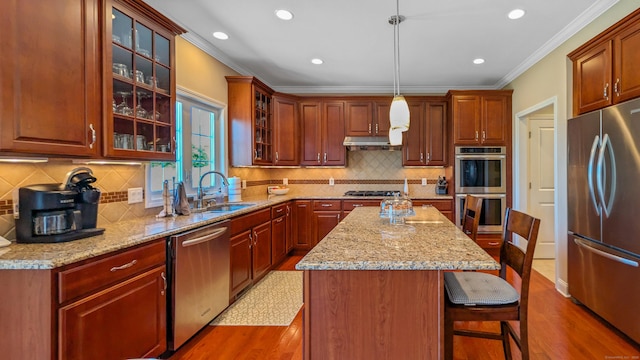 753 N Farms Rd, Wallingford, CT 06492 - kitchen with stainless steel appliances, a sink, crown molding, wood finished floors, and a kitchen bar