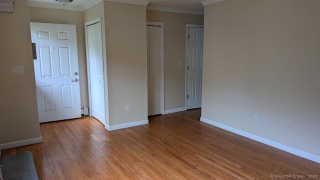 70 Lantern Park Dr Unit 1, Naugatuck, CT 06770 - unfurnished bedroom featuring baseboards, crown molding, light wood-style flooring, and multiple closets