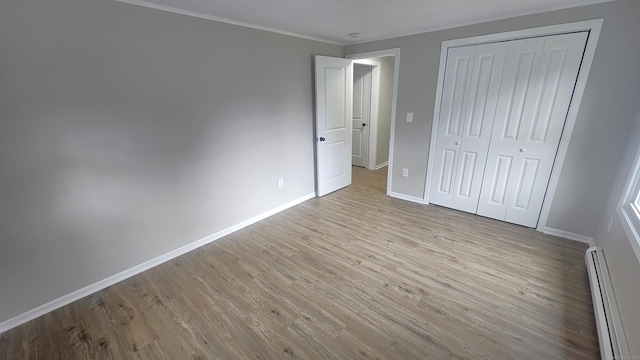 3 Norwood Ave, New London, CT 06320 - unfurnished bedroom featuring a baseboard heating unit, wood finished floors, baseboards, ornamental molding, and a closet