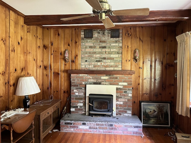 47 Devaux Rd, Torrington, CT 06790 - living room featuring a wood stove, wood finished floors, a ceiling fan, wood walls, and beamed ceiling