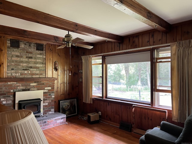 47 Devaux Rd, Torrington, CT 06790 - living area with beamed ceiling, a wood stove, wood finished floors, wooden walls, and ceiling fan