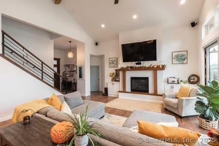 43B Saunders Hollow Rd, Old Lyme, CT 06371 - living area with stairs, high vaulted ceiling, a fireplace with raised hearth, wood finished floors, and recessed lighting
