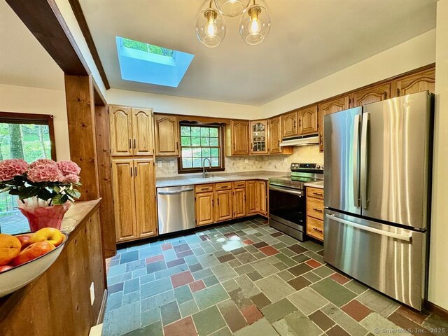 687 Sprout Brook Rd, Putnam Valley, NY 10579 - kitchen with appliances with stainless steel finishes, under cabinet range hood, a skylight, brown cabinets, and light countertops