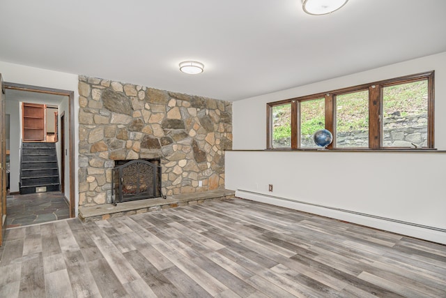 14 Old Bridge Rd W, New Fairfield, CT 06812 - unfurnished living room with a baseboard heating unit, wood finished floors, a stone fireplace, and stairway