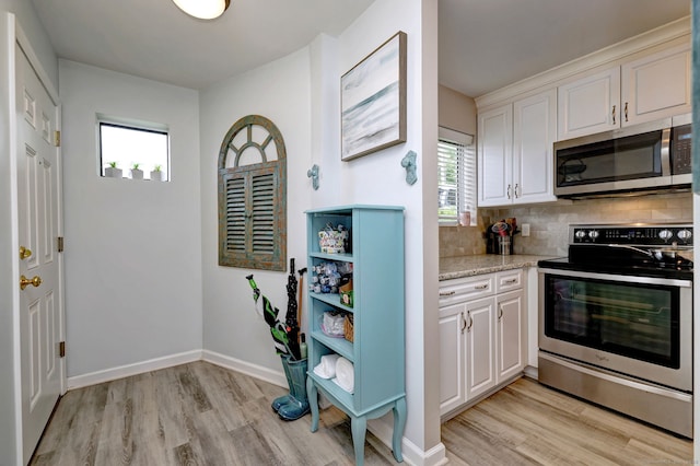 267 Melba St Apt D2, Milford, CT 06460 - kitchen with stainless steel appliances, light wood-style floors, tasteful backsplash, and white cabinets