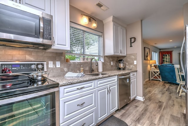 267 Melba St Apt D2, Milford, CT 06460 - kitchen featuring stainless steel appliances, white cabinets, tasteful backsplash, and light wood-style floors