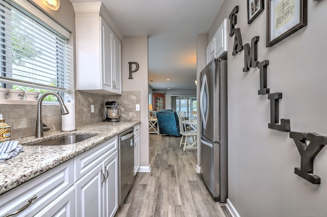 267 Melba St Apt D2, Milford, CT 06460 - kitchen featuring appliances with stainless steel finishes, light wood-type flooring, white cabinets, decorative backsplash, and light stone countertops