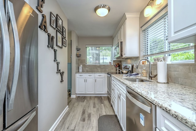 267 Melba St Apt D2, Milford, CT 06460 - kitchen with stainless steel appliances, light wood-type flooring, decorative backsplash, and white cabinets