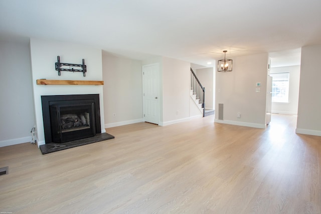 14 Hubbard Run Dr Unit 14, Glastonbury, CT 06033 - unfurnished living room with stairs, light wood finished floors, a chandelier, a fireplace with raised hearth, and baseboards