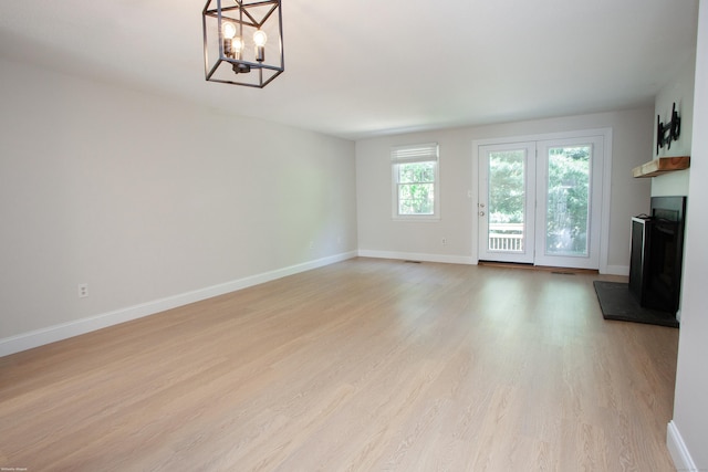 14 Hubbard Run Dr Unit 14, Glastonbury, CT 06033 - unfurnished living room featuring light wood-style flooring, a chandelier, baseboards, and a fireplace with raised hearth