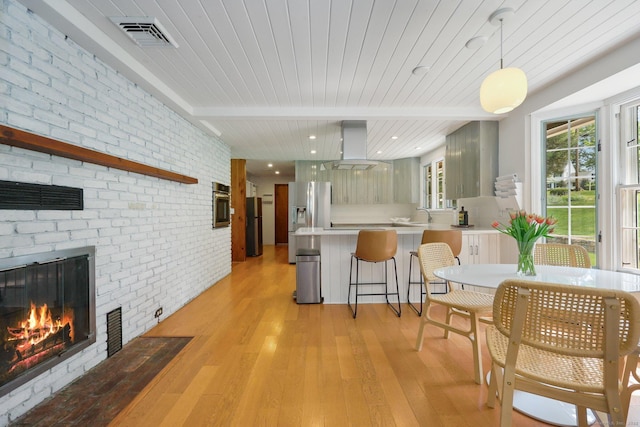 58 Lantern Ridge Rd, New Canaan, CT 06840 - kitchen with island exhaust hood, stainless steel appliances, light wood-style floors, light countertops, and brick wall