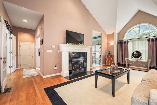 136 Thistle Pond Dr Unit 136, Bloomfield, CT 06002 - living room with wood finished floors, baseboards, vaulted ceiling, a glass covered fireplace, and decorative columns
