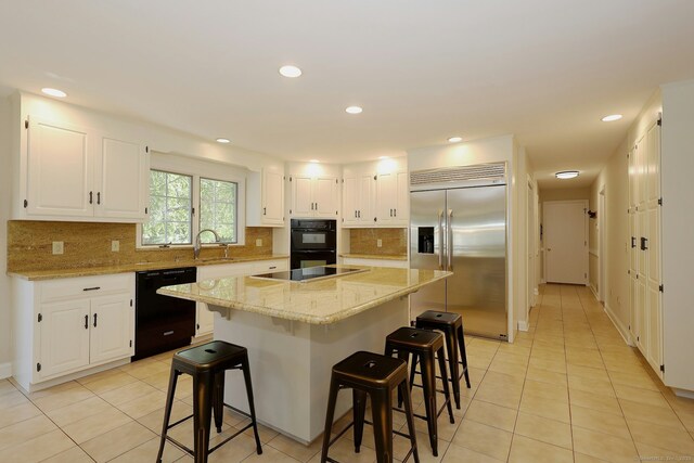 108 Northwood Dr, Easton, CT 06612 - kitchen with black appliances, a kitchen island, a kitchen bar, light stone counters, and recessed lighting