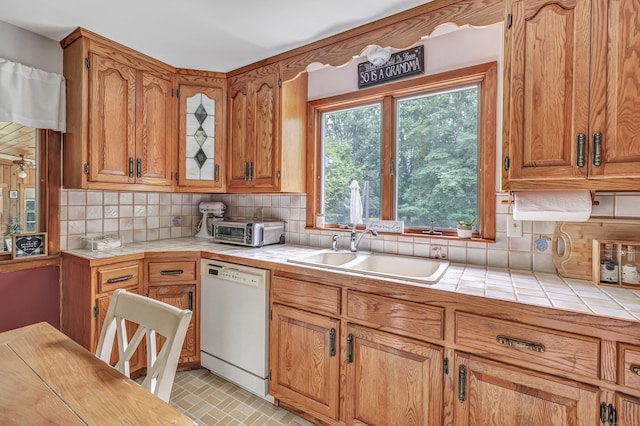 131 Ridgeview Ave, Trumbull, CT 06611 - kitchen with white dishwasher, tile counters, a sink, backsplash, and brick patterned flooring