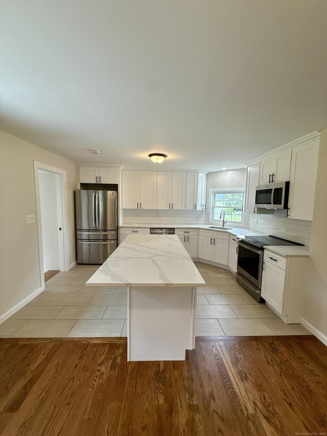 9 Grieb Rd, Wallingford, CT 06492 - kitchen featuring stainless steel appliances, a sink, a center island, backsplash, and white cabinets