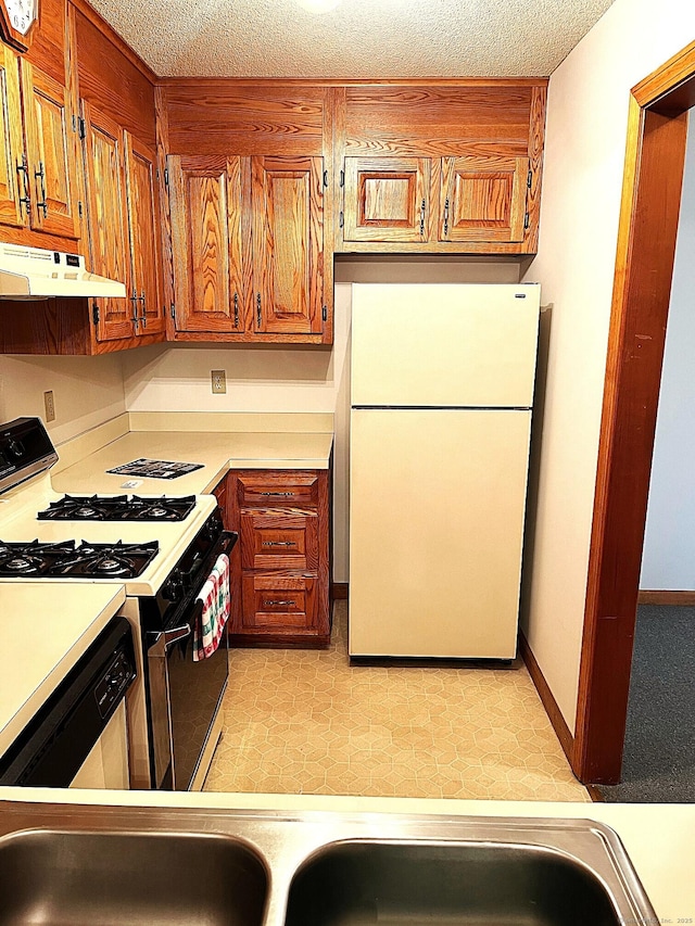 366 Ash St # 31, Windham, CT 06226 - kitchen with freestanding refrigerator, range with gas stovetop, under cabinet range hood, light countertops, and brown cabinetry