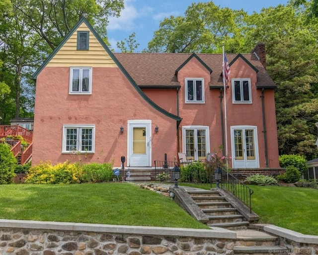73 Hemlock Rd, New Haven, CT 06515 - tudor-style house featuring a chimney, stucco siding, a front yard, roof with shingles, and stairway
