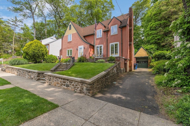 73 Hemlock Rd, New Haven, CT 06515 - view of front of home featuring an outdoor structure, a detached garage, a front yard, a chimney, and stucco siding