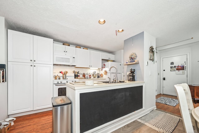 26 Evergreen Rd Unit 26, Torrington, CT 06790 - kitchen featuring white appliances, a sink, white cabinets, a peninsula, and wood finished floors