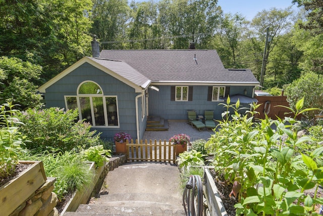 56 Giants Neck Rd, East Lyme, CT 06357 - view of front of house featuring a shingled roof, a chimney, a patio, and view of scattered trees